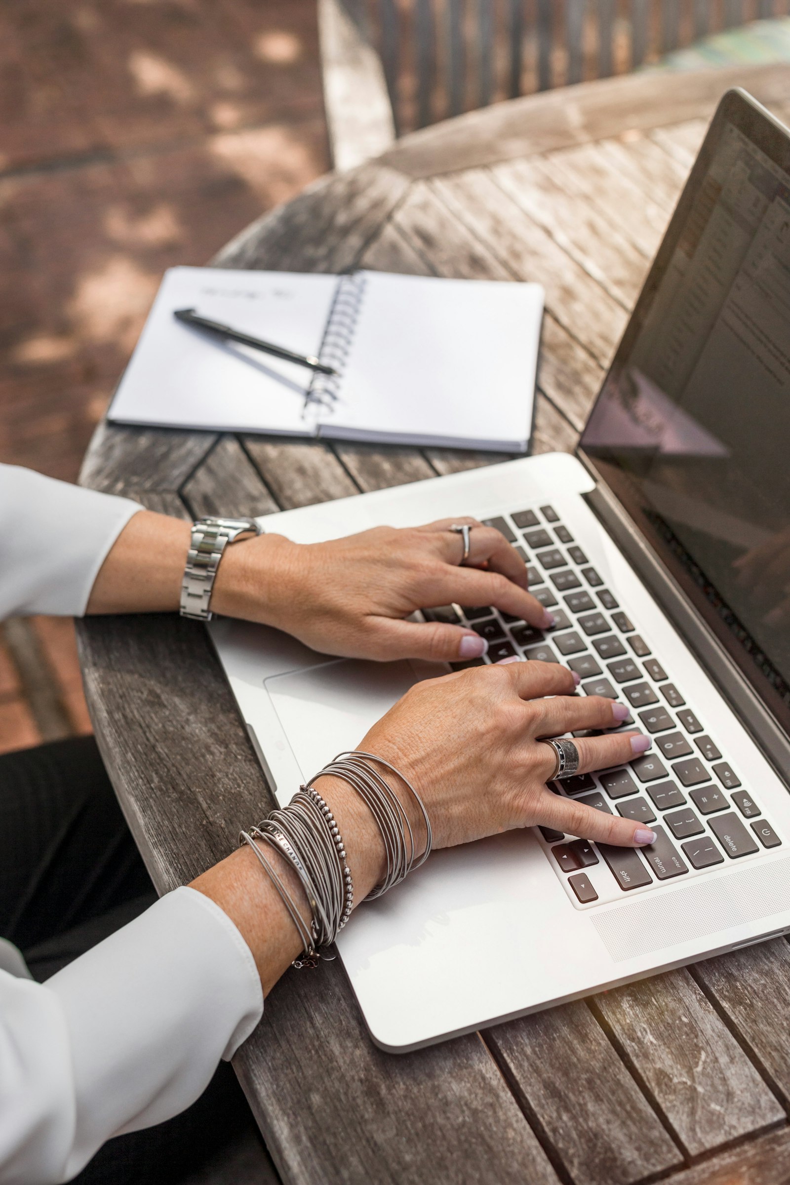 Hands typing on a laptop beside a notebook, preparing translated chat evidence for a visa application